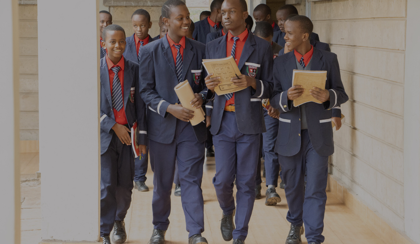 PCEA Enoomatasiani Booth Boys High School of Excellence boys walking at the corridor while holding A4 books